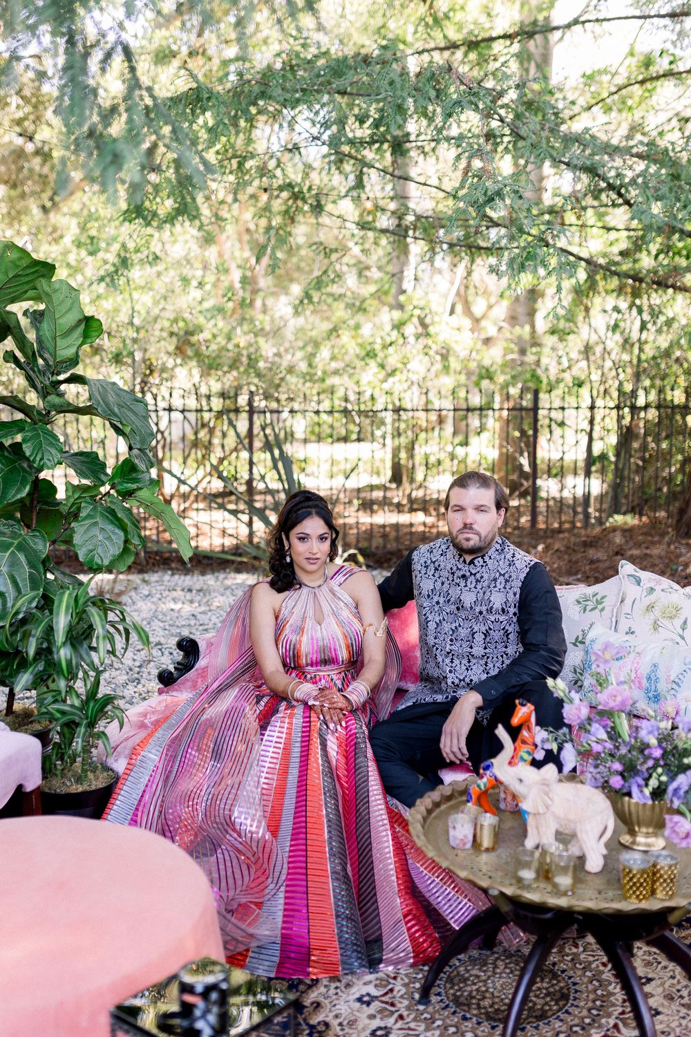 Couple sharing intimate moments on pink cushions in an enchanted forest setting with decorative elements.
