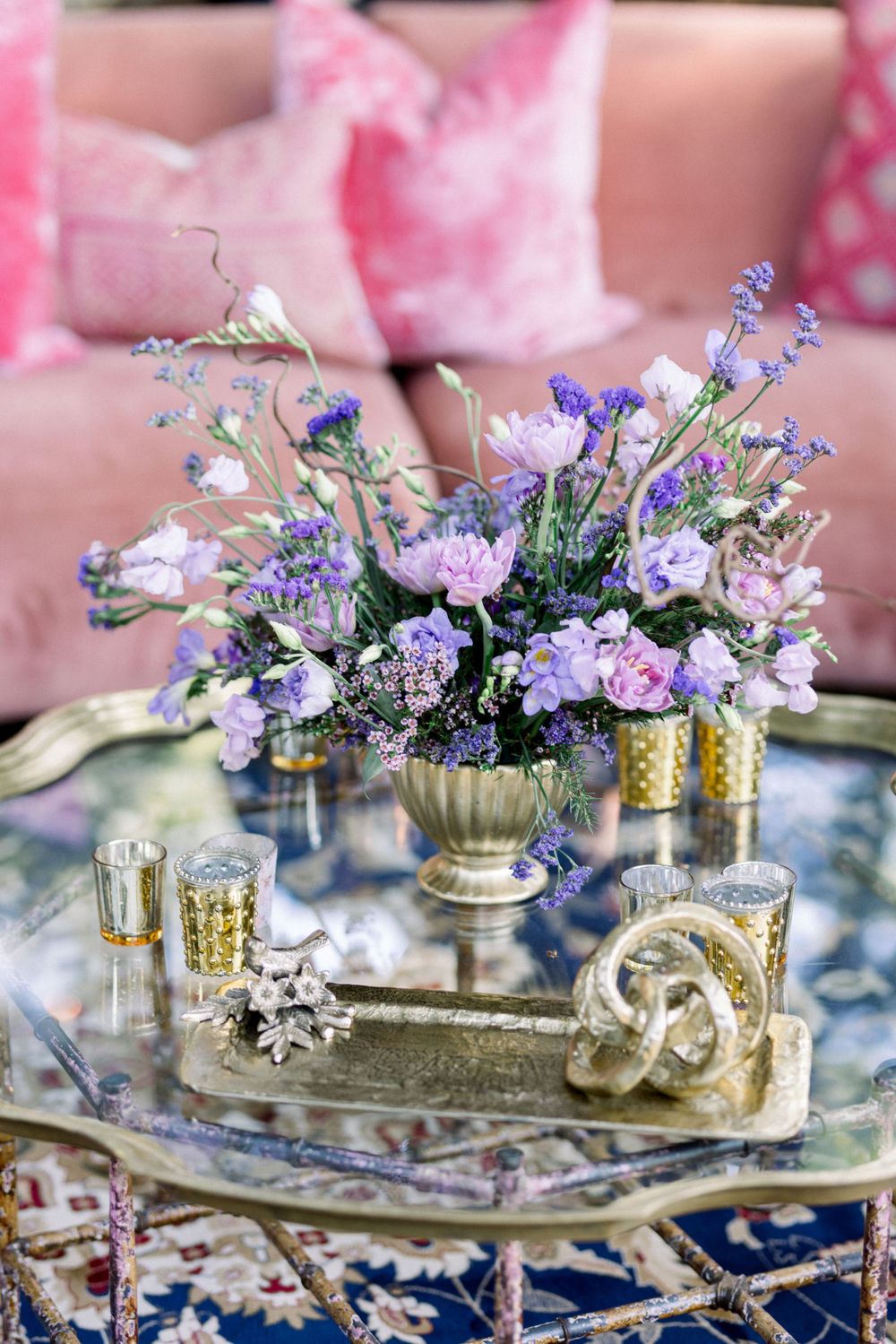 Elegant table setting with purple flowers in gold vases on mirrored tray creating romantic ambiance.