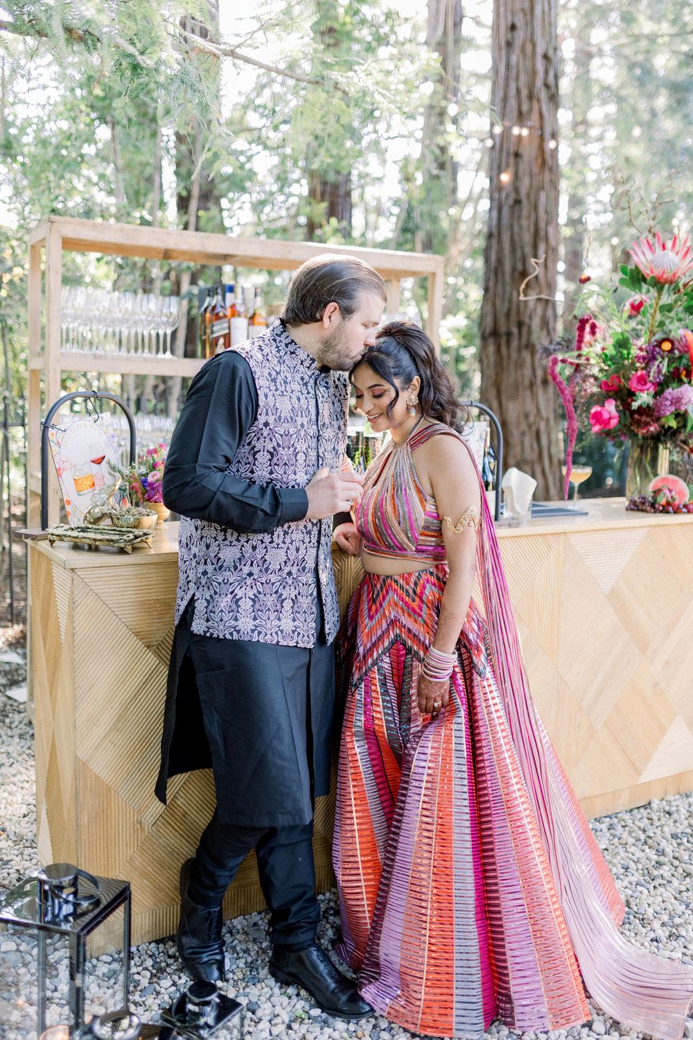 Romantic garden photoshoot featuring couple near wooden bar with floral decorations.