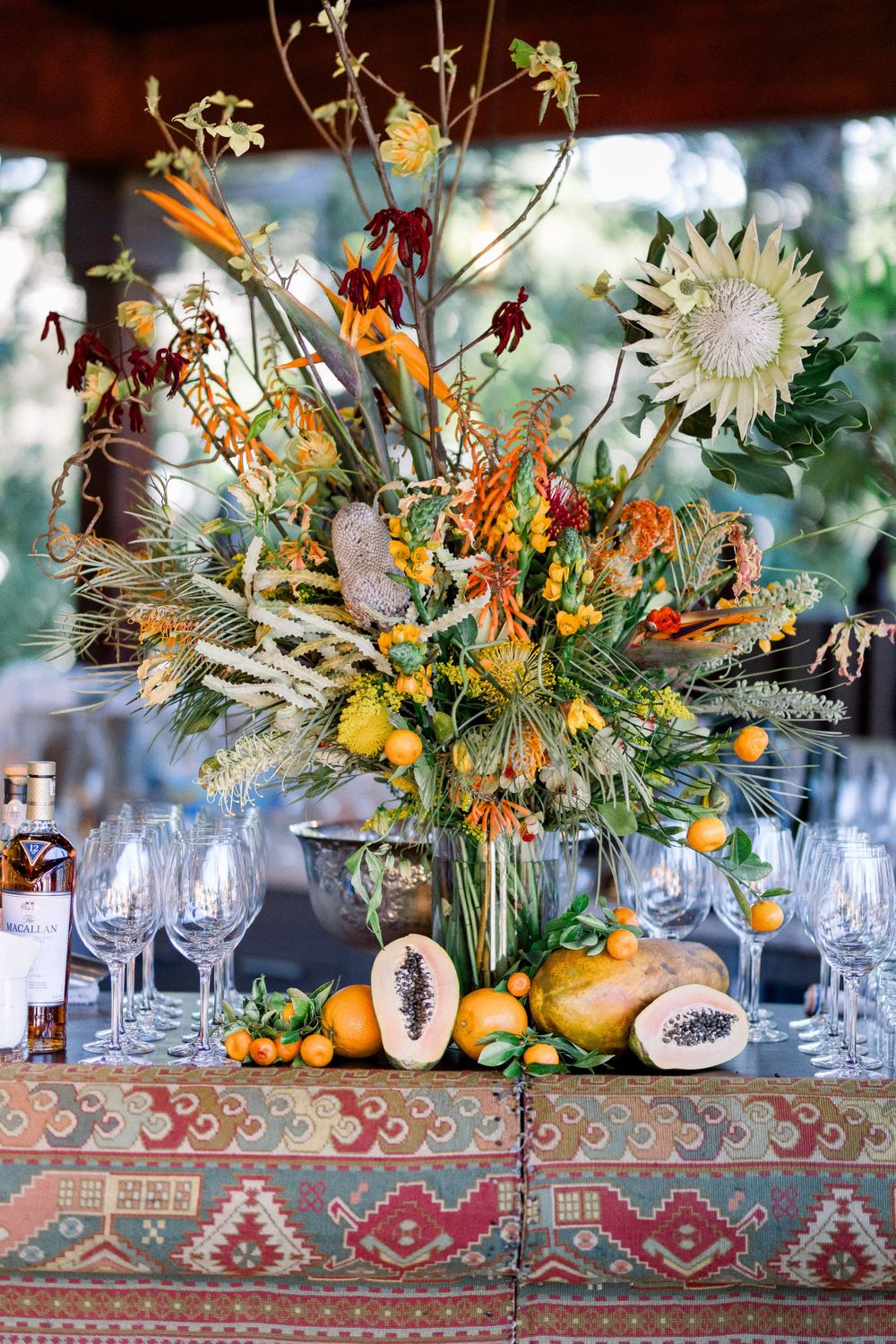 Elegant table display with autumn floral arrangements, gourds, and wine glasses on a decorative tiled surface.