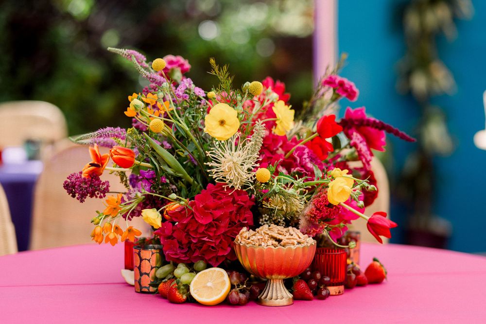 Vibrant floral arrangements with citrus accents displayed on pink tablecloths.