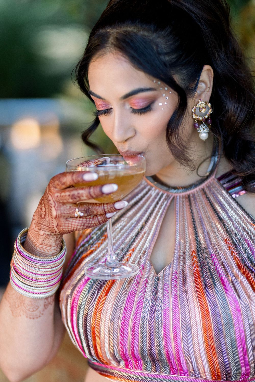 Close-up details of pink and orange striped high-neck dress with henna decorated hands.