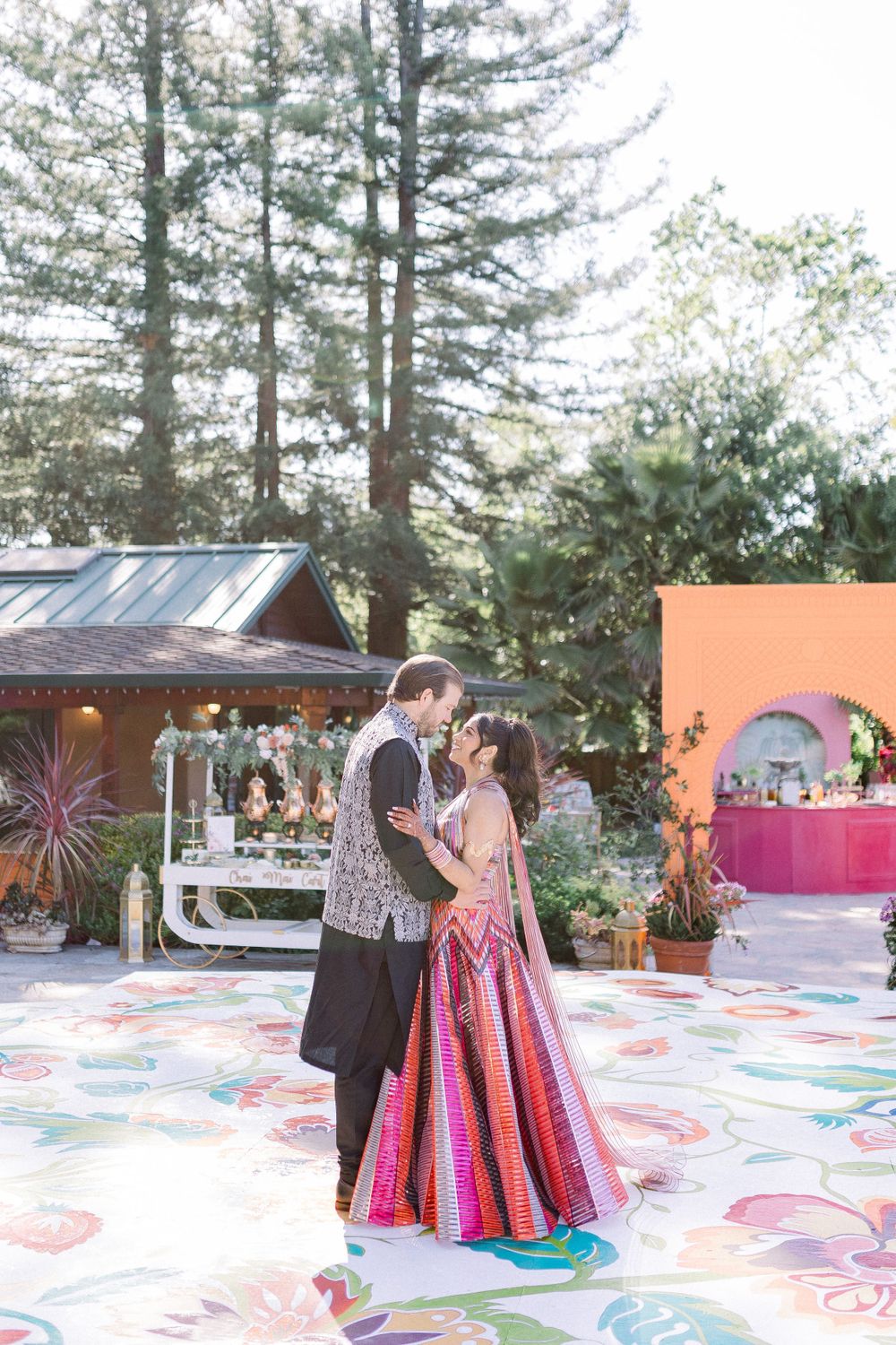 An outdoor celebration featuring a colorfully decorated patio space with pine trees in the background.