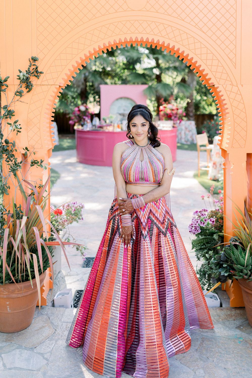 Elegant peach archway framing a garden party setting with a pink bar in the background.