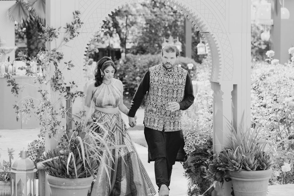 Black and white photo showing an outdoor celebration under a garden gazebo with floral arrangements.