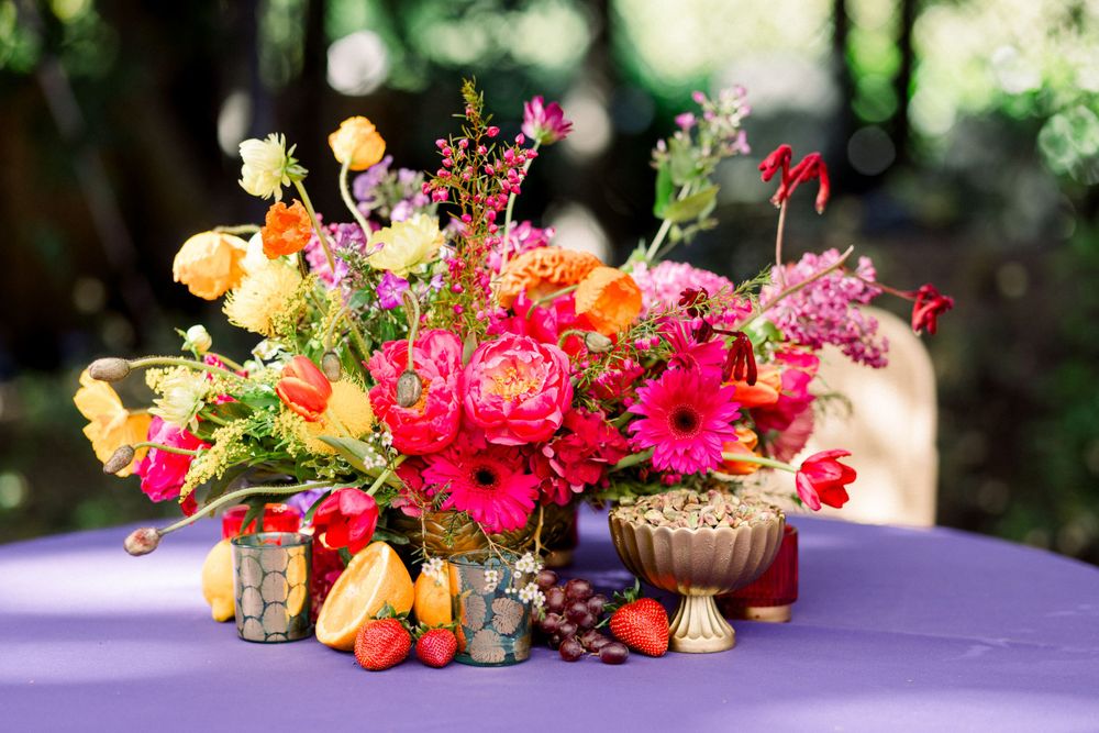 Vibrant floral arrangements with pink and orange blooms displayed on a purple tablecloth.