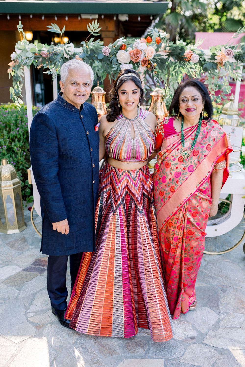 Group portrait at outdoor celebration wearing traditional Indian and fusion formal attire.