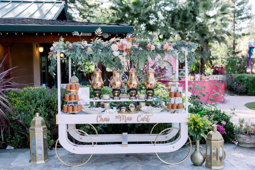 Decorated outdoor party space with white furniture and floral arrangements.