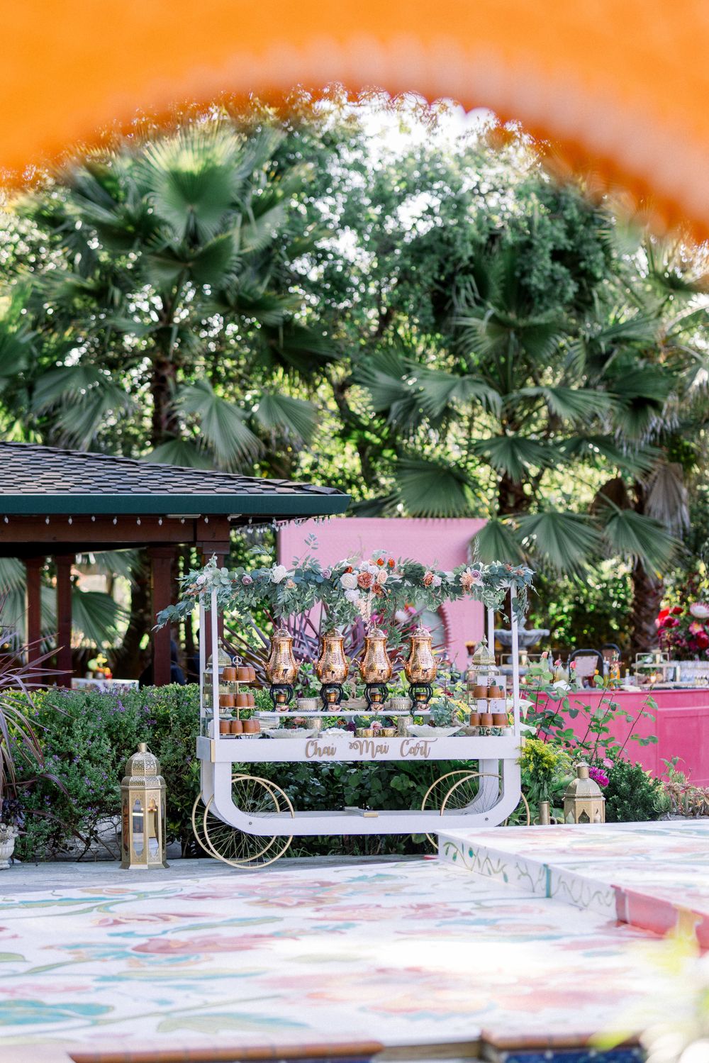 Outdoor event space decorated with pink walls and palm trees creating a tropical ambiance.