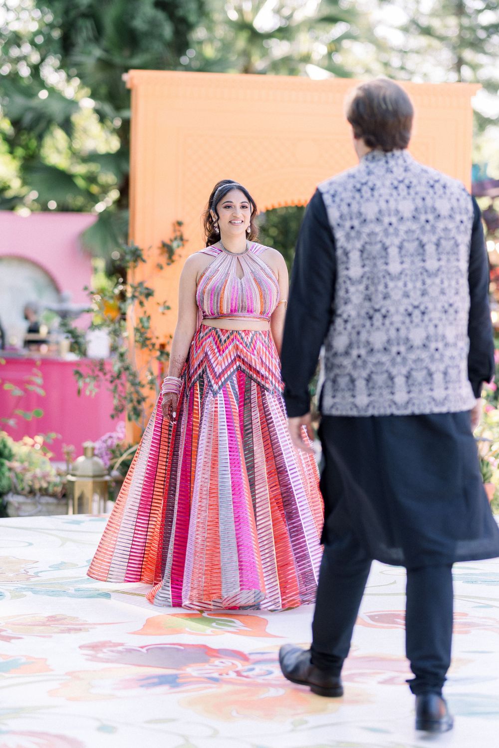Dance sequence on a colorful patio featuring a pink and red patterned dress.