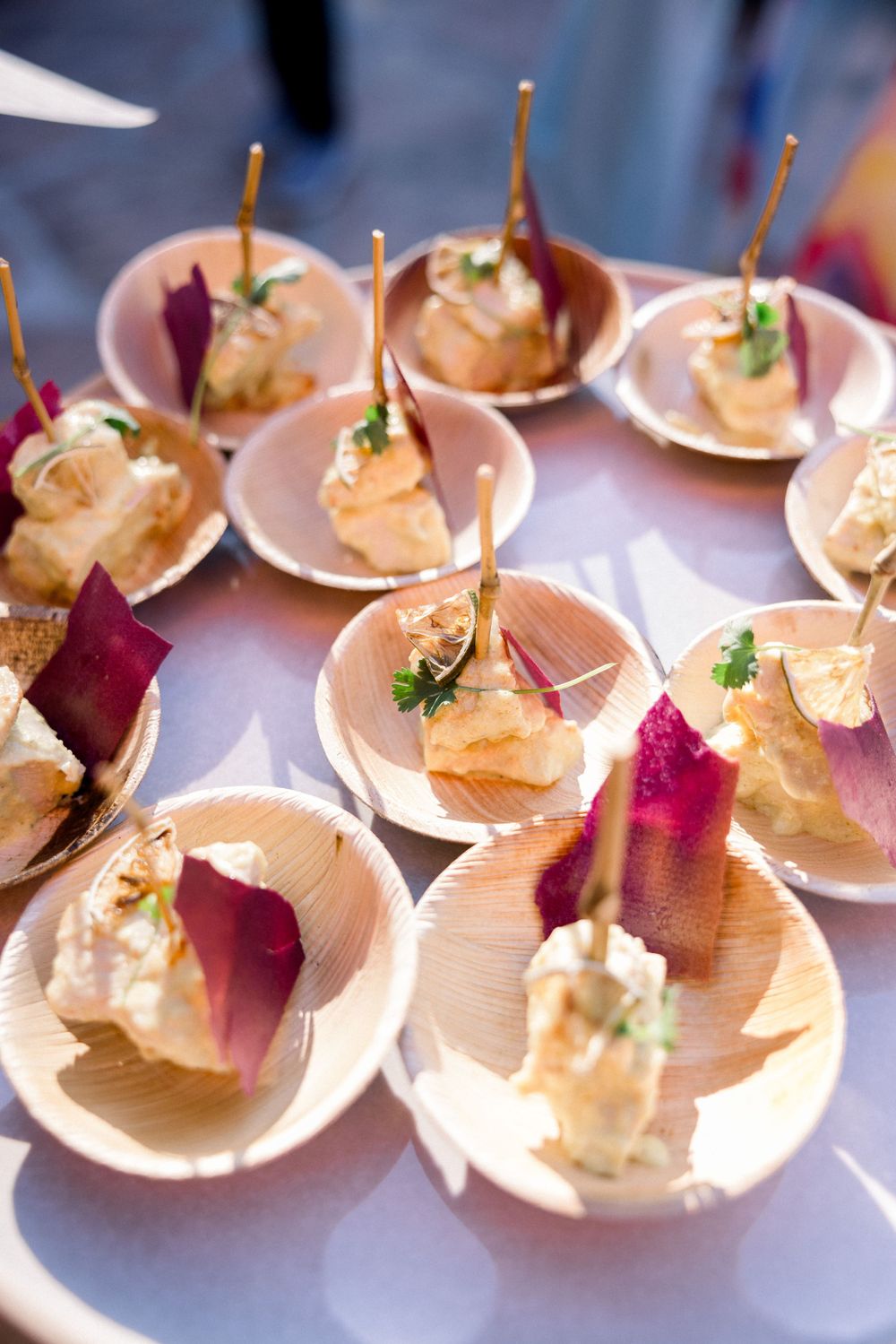 Elegant appetizer bites served on small white plates with red garnish and fresh herbs.