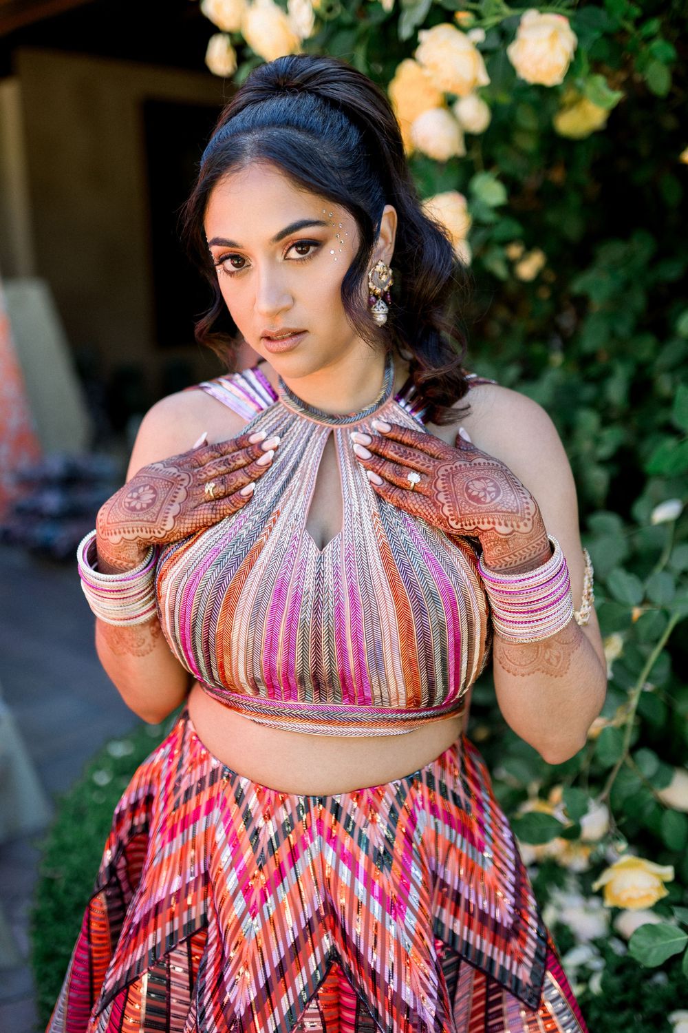Close up shots of a vibrant striped dress with intricate henna designs on hands.