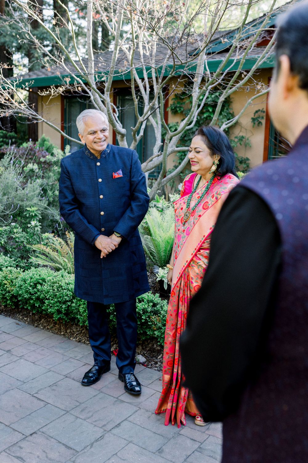 Couple in traditional Indian attire at an outdoor garden celebration.