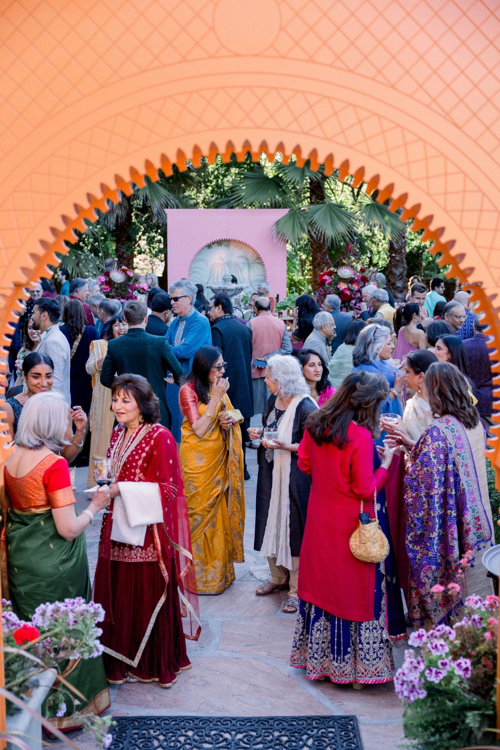Colorful crowd gathering under an ornate archway at a cultural celebration.