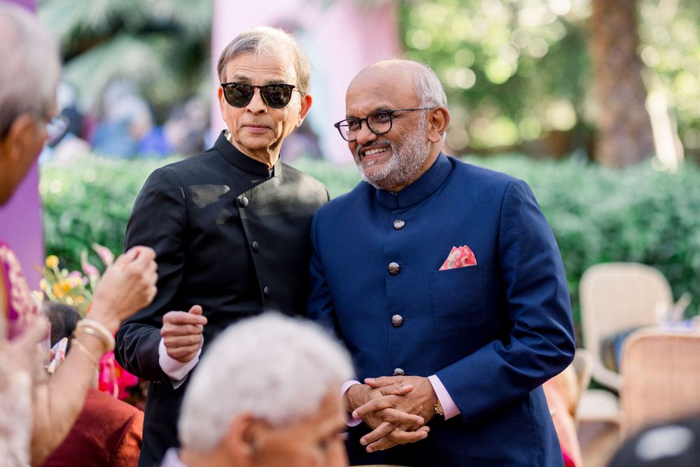 Two guests in formal navy blue attire sharing a moment at an outdoor celebration.
