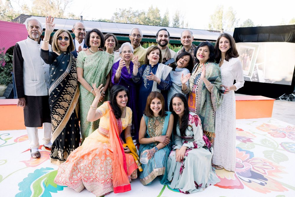 Group photo of celebration attendees in colorful traditional Indian attire on a painted patio.