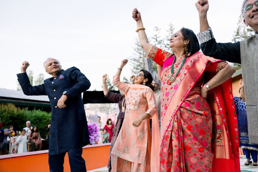 Guests dancing with raised arms at an outdoor wedding reception.