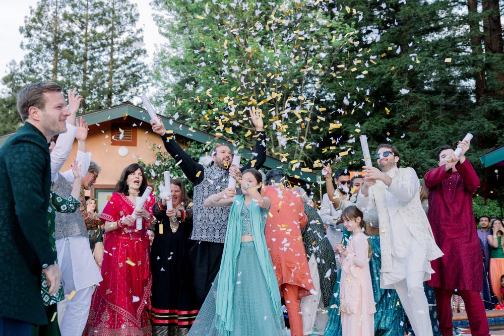 Festive outdoor celebration with confetti falling as guests dance in formal wear.