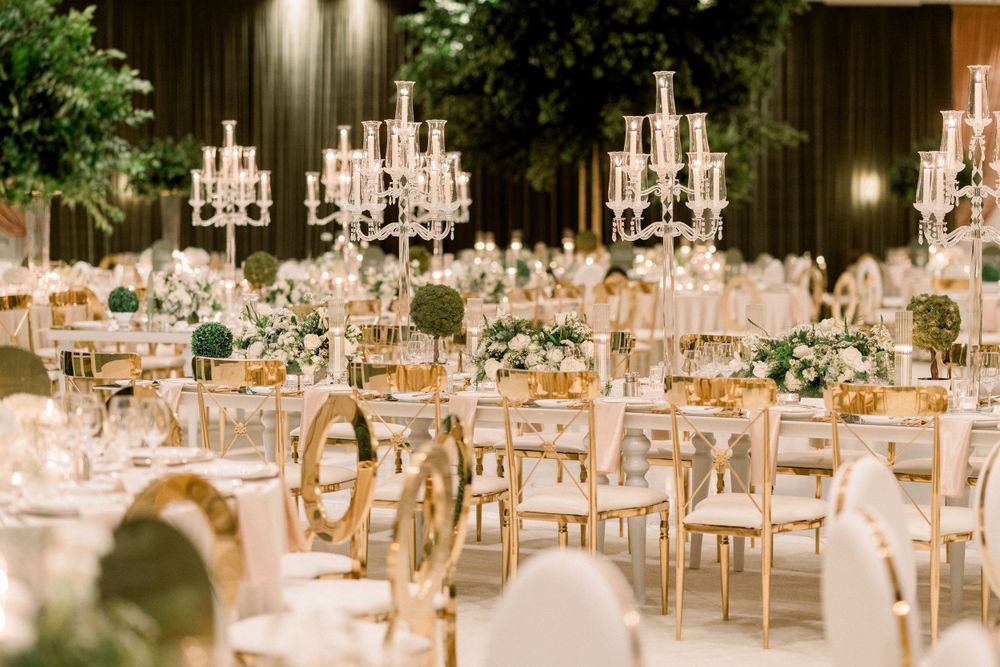 Elegant wedding reception hall with crystal chandeliers and golden chairs arranged for dining.