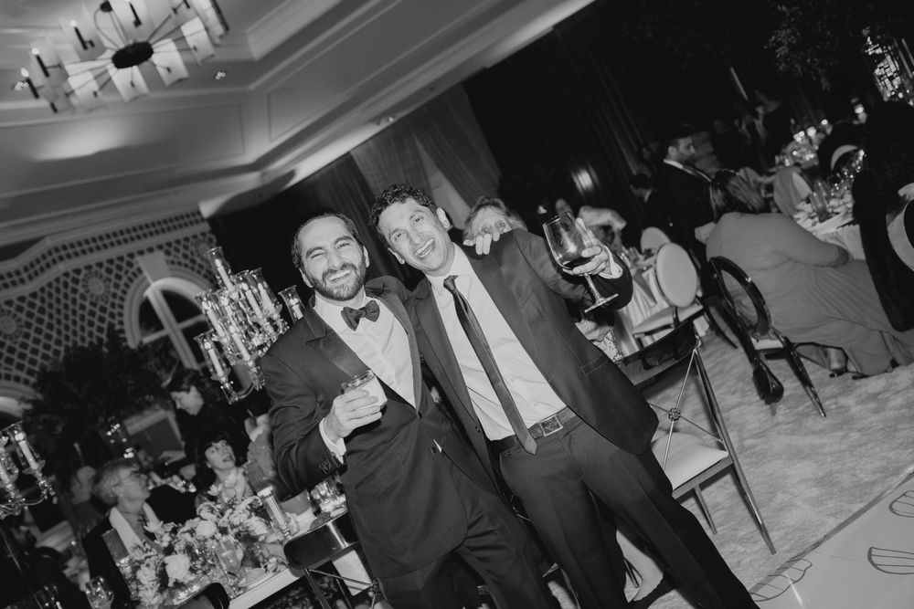 Black and white photo of wedding guests celebrating enthusiastically on dance floor.