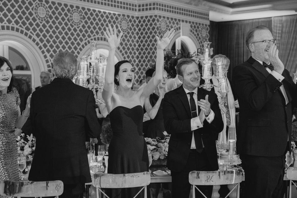 Black and white candid reception photo capturing celebratory toast moments.