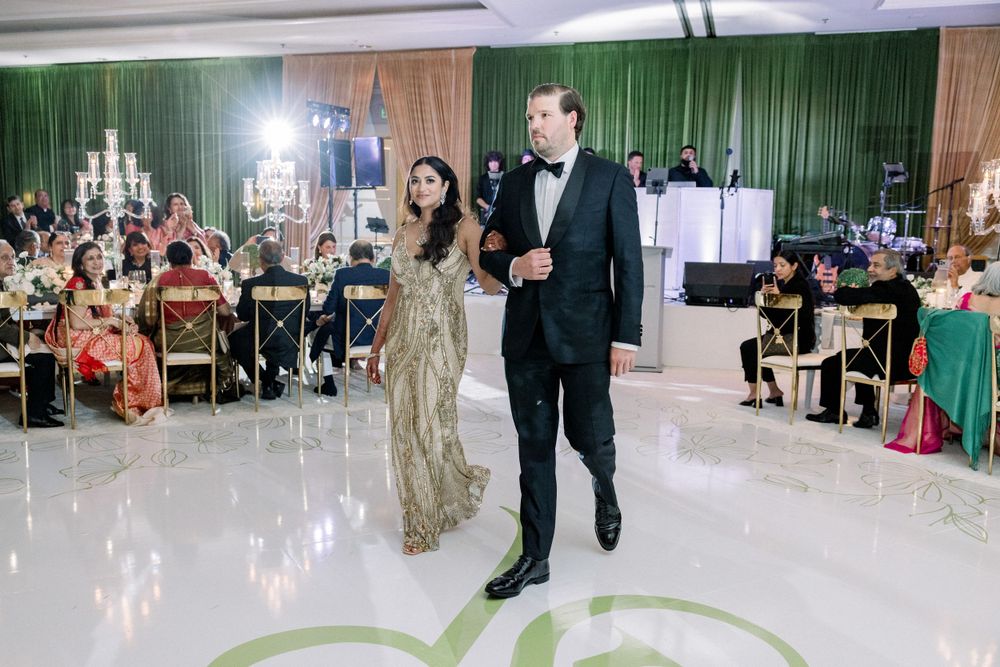 Couple dancing on reflective floor during wedding reception with elegant decor.