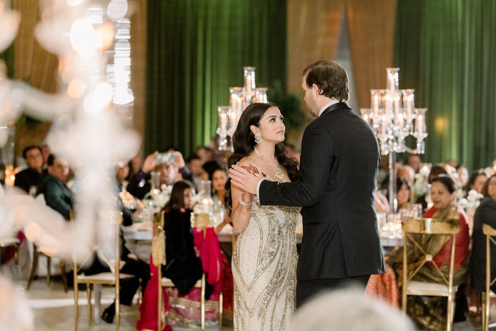 Intimate dance moment at wedding reception with elegant gold dress and green backdrop.
