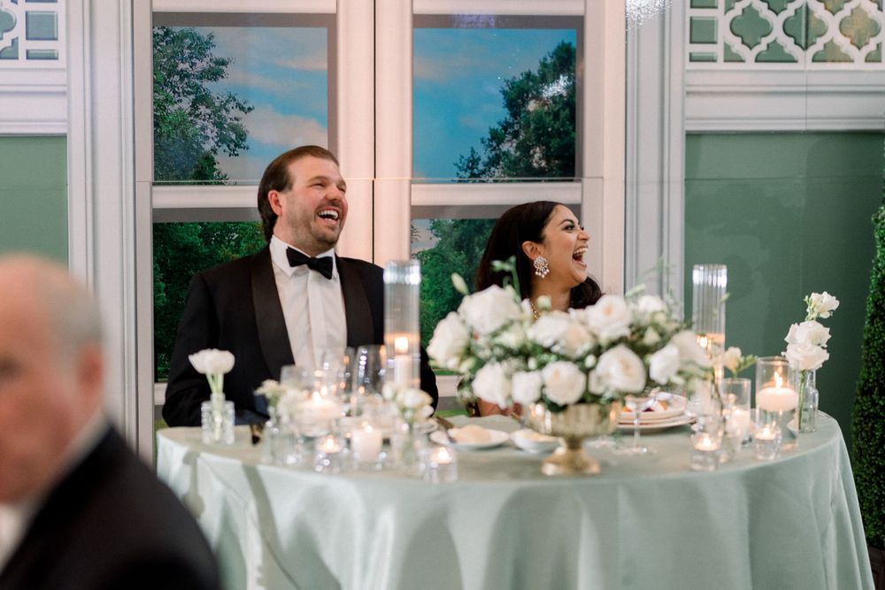 Joyful moment shared at an elegant wedding reception table with white floral centerpieces.