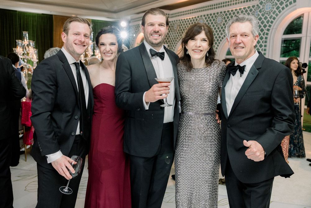 Formal evening event with guests in elegant attire mingling at a decorated venue.