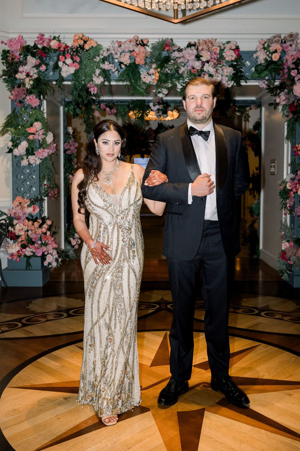 Elegant ballroom entrance decorated with pink and white floral arrangements and ornate flooring.