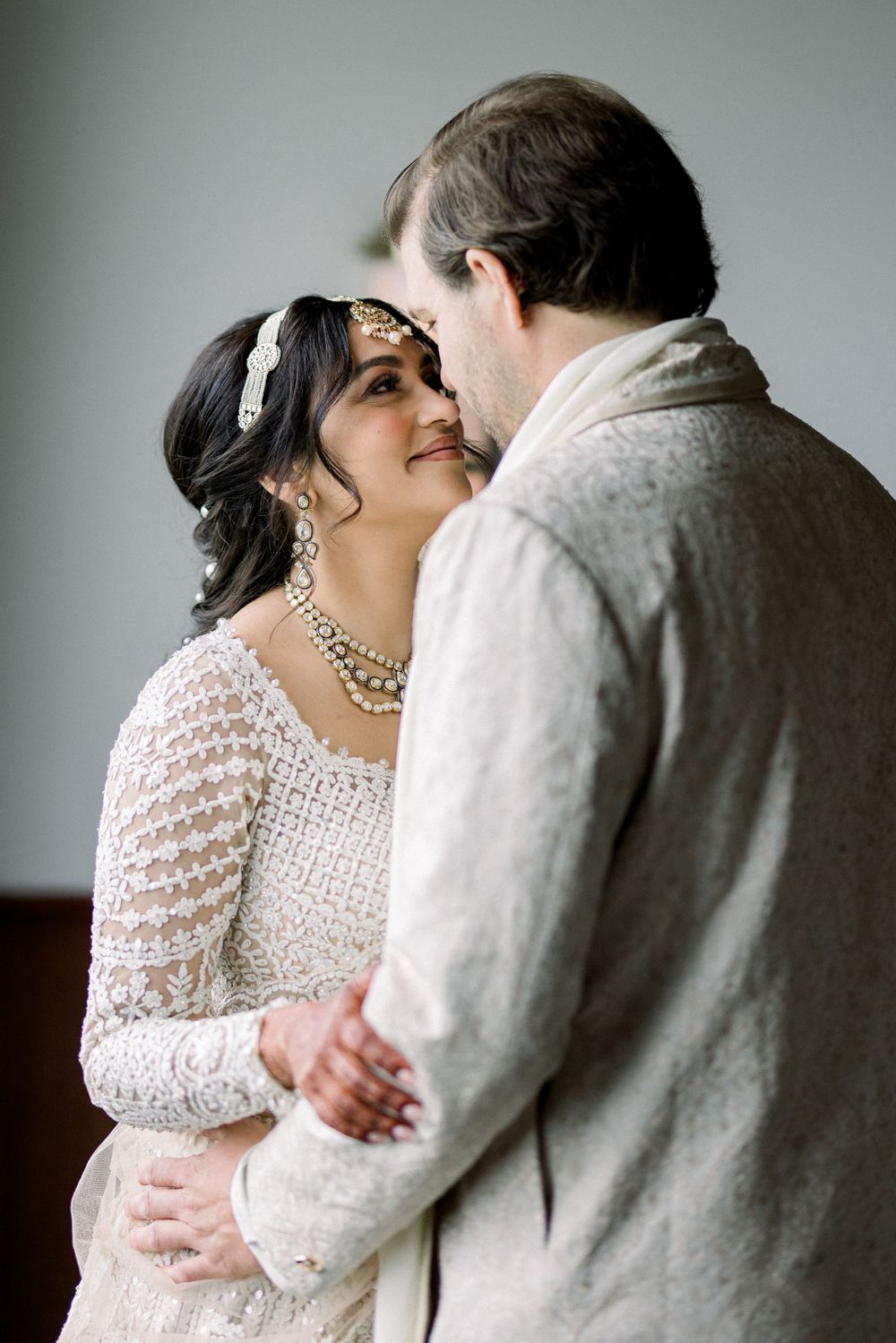 Intimate portrait of a couple embracing in elegant wedding attire.