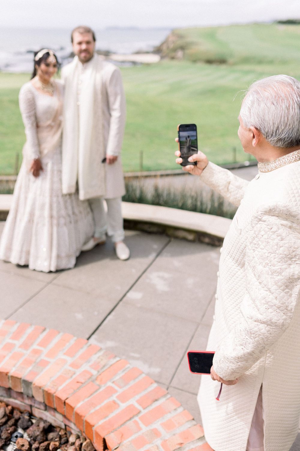 Wedding photography session with guests taking pictures on a coastal terrace.