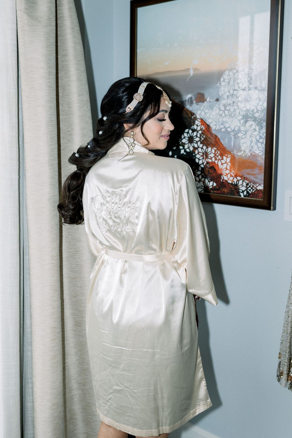 White silk robes hanging in a dressing room with mirrors and soft lighting.