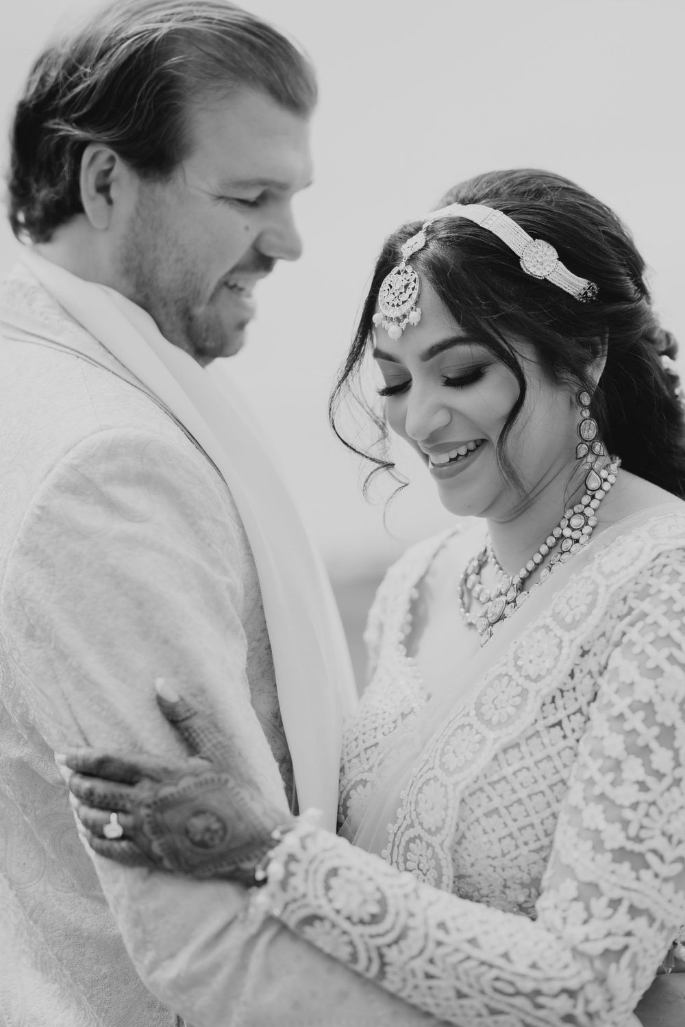 Black and white romantic portrait of a couple sharing an intimate moment in formal wedding attire.