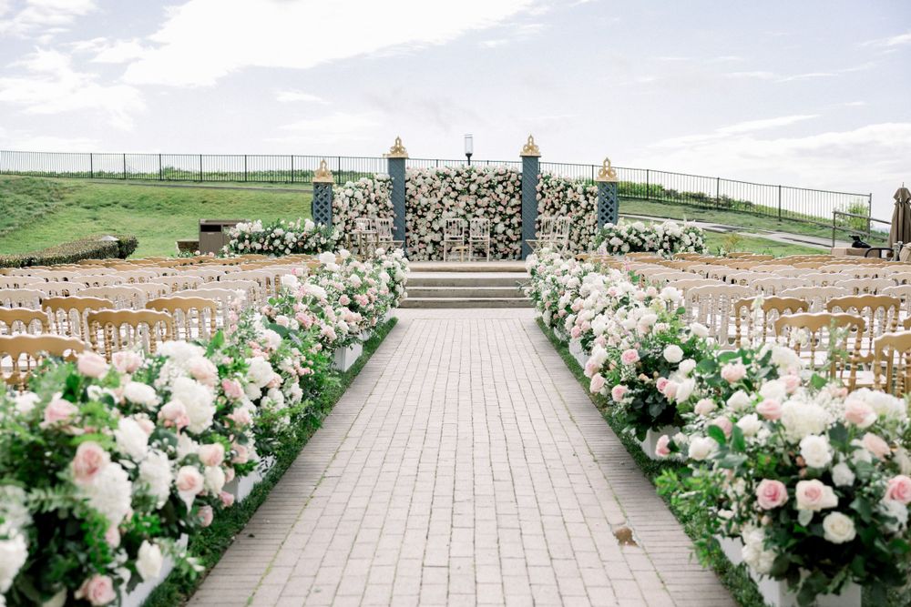 Wedding ceremony aisle decorated with white floral arrangements along a stone pathway overlooking the ocean.
