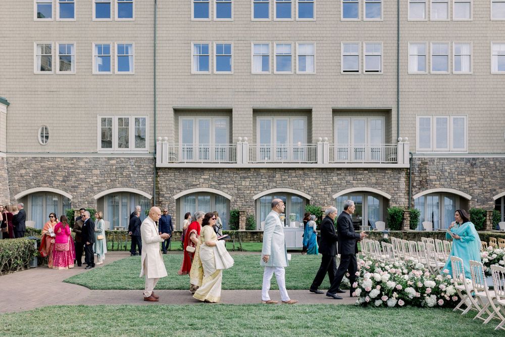 Wedding party gathered outside a grand stone building with arched windows.