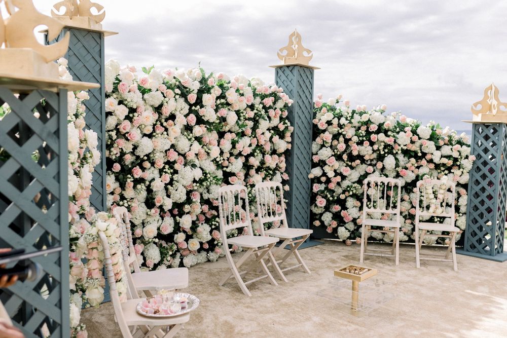 Wedding venue decorated with lush white and pink floral arrangements along lattice walls.