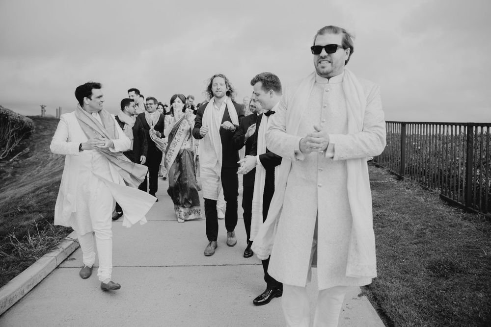 Black and white photo of guests mingling at an outdoor wedding celebration.
