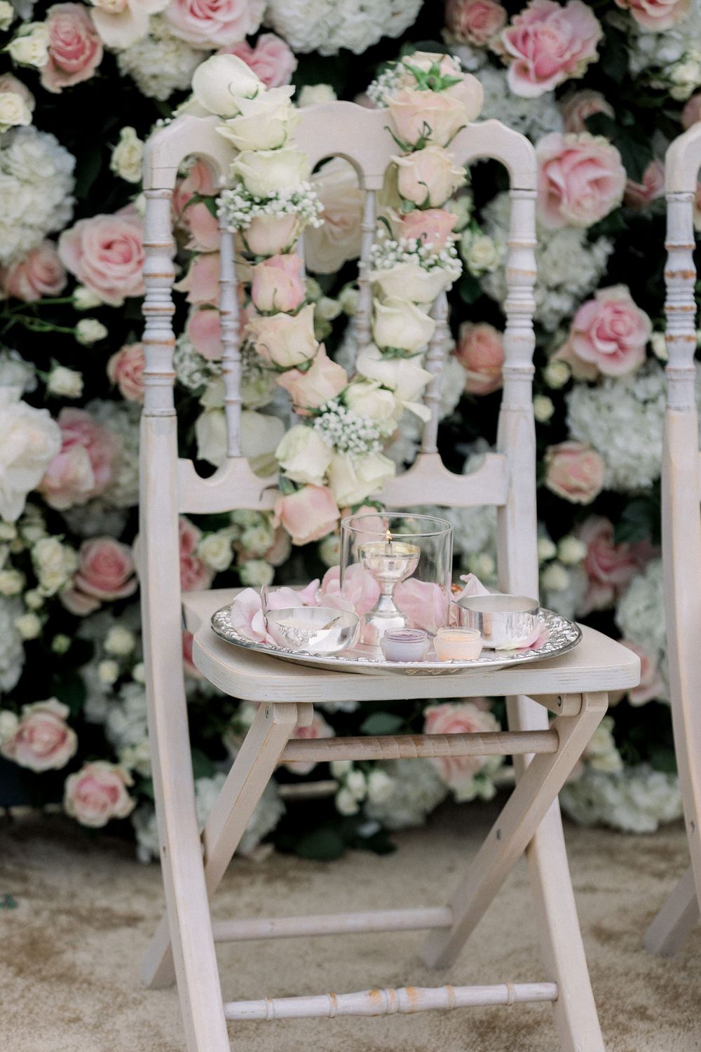 Elegant wedding reception setup with pink and white rose floral arch and table settings.