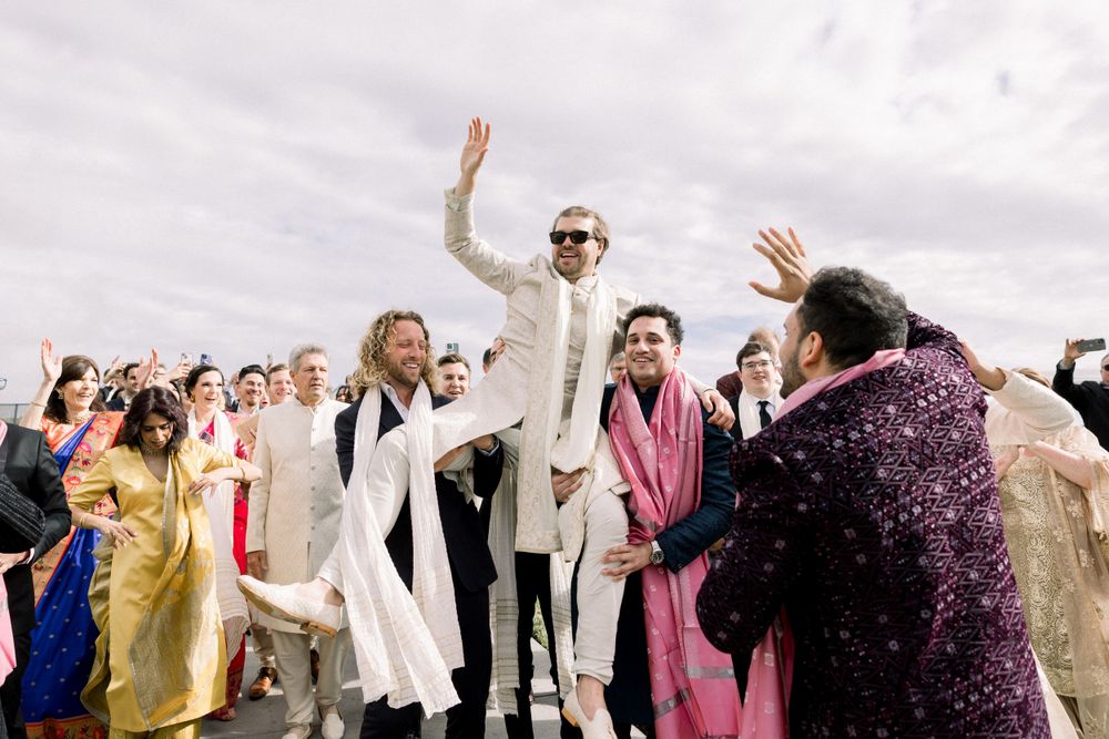Wedding guests celebrate and dance together at an outdoor venue.