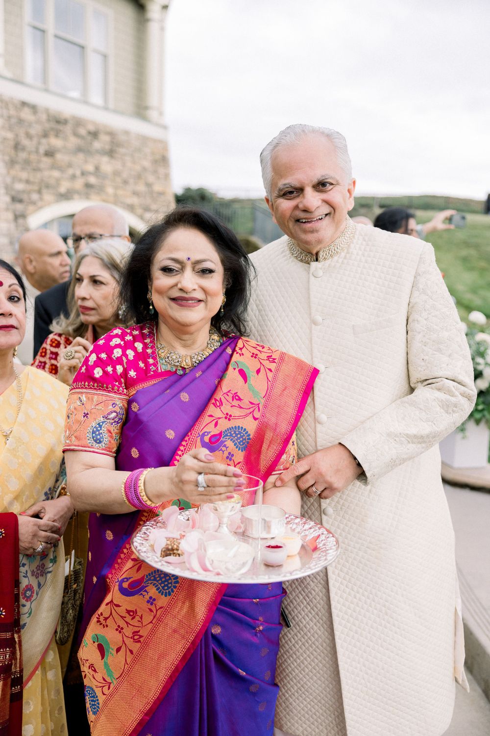 Wedding guests in colorful saris enjoying refreshments at an elegant outdoor reception.
