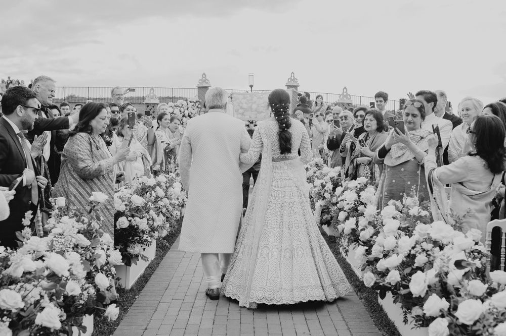 Wedding ceremony on a stone patio with white floral decorations and seated guests.