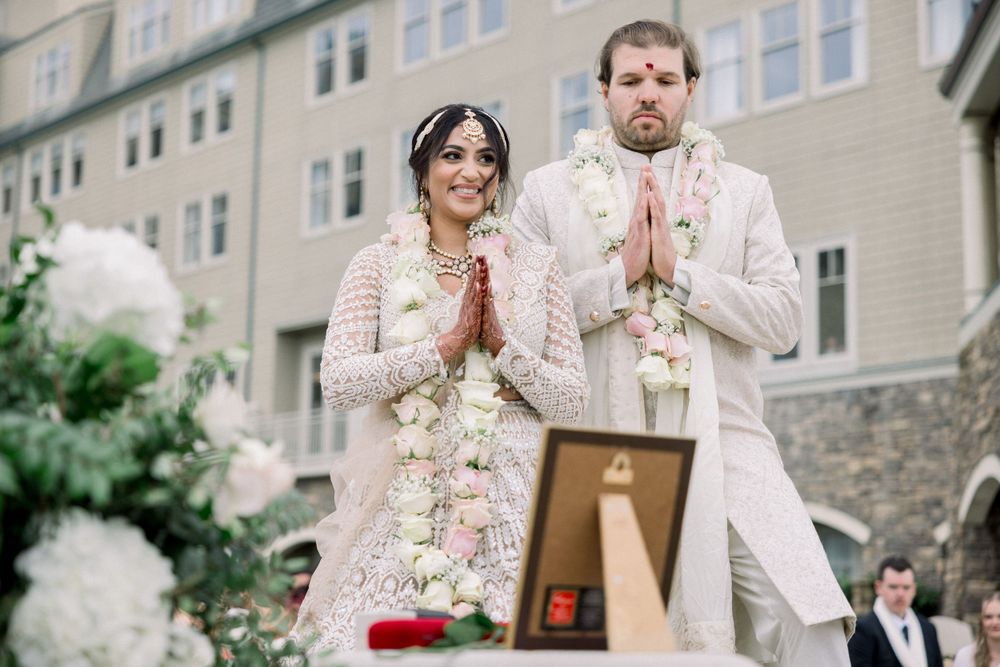 Couple in elegant white and cream outfits standing together at their wedding ceremony.