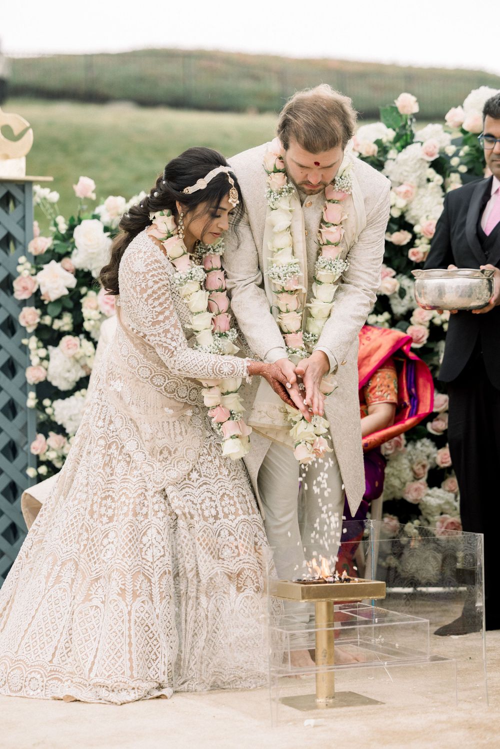 Traditional wedding ritual being performed with floral garlands and decorative backdrop.