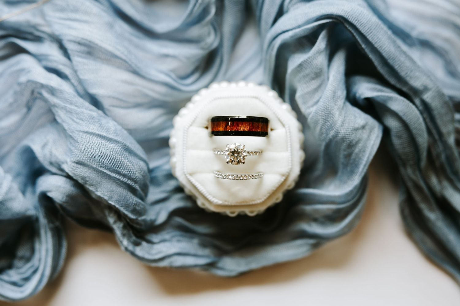 Wedding rings nestled among white roses and delicate veil fabric.