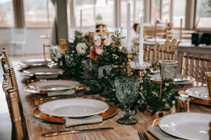 An elegant wedding table setting with floral centerpieces and gold chairs.