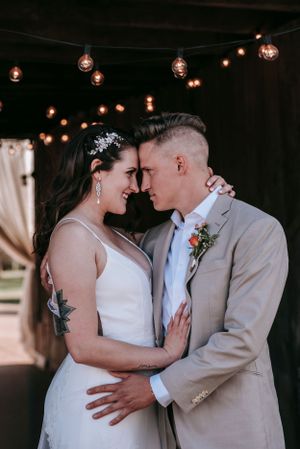 A joyful wedding moment captured under warm string lights with the couple sharing an intimate embrace.
