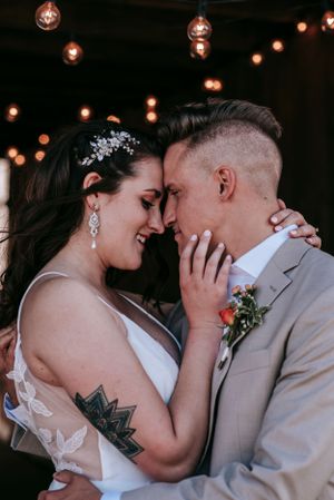 An emotional wedding portrait showing a tender embrace under glowing string lights.