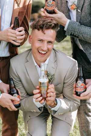 Wedding party member in light suit enjoying drinks with friends.