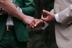 Close-up shot of hands exchanging rings during outdoor wedding ceremony.
